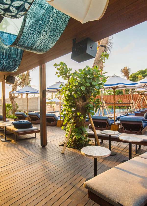 A deck with lounge furniture next to a hotel pool.