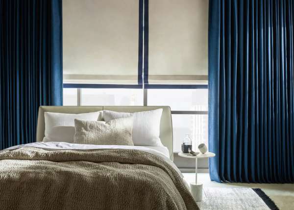 A hotel room and bed with blue drapery made with Sunbrella fabrics.