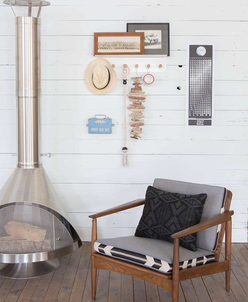 Coussins de tons gris en tissus Pendleton par Sunbrella sur une chaise en bois à côté d’une cheminée moderne.