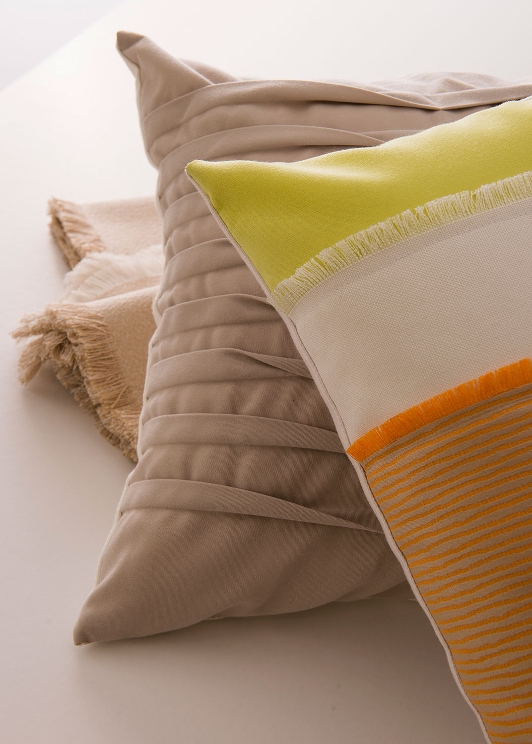 Ingrandimento di cuscini di colore neutro con accenti arancio e giallo limone.