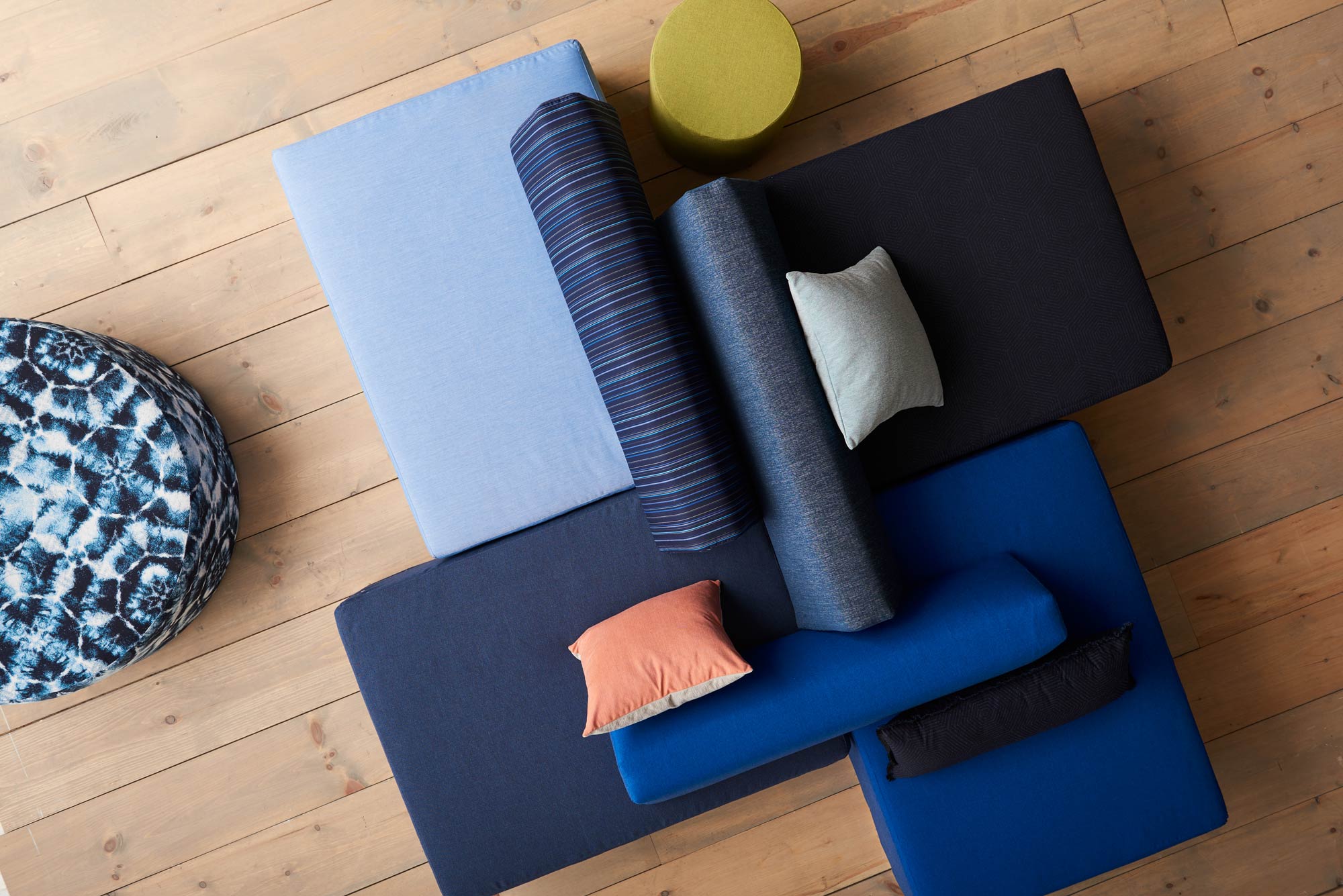 Foto aérea de quatro calçadeiras quadradas com almofadas redondas e decorativas, estofadas com tecidos de desempenho da Sunbrella Pure Collection.