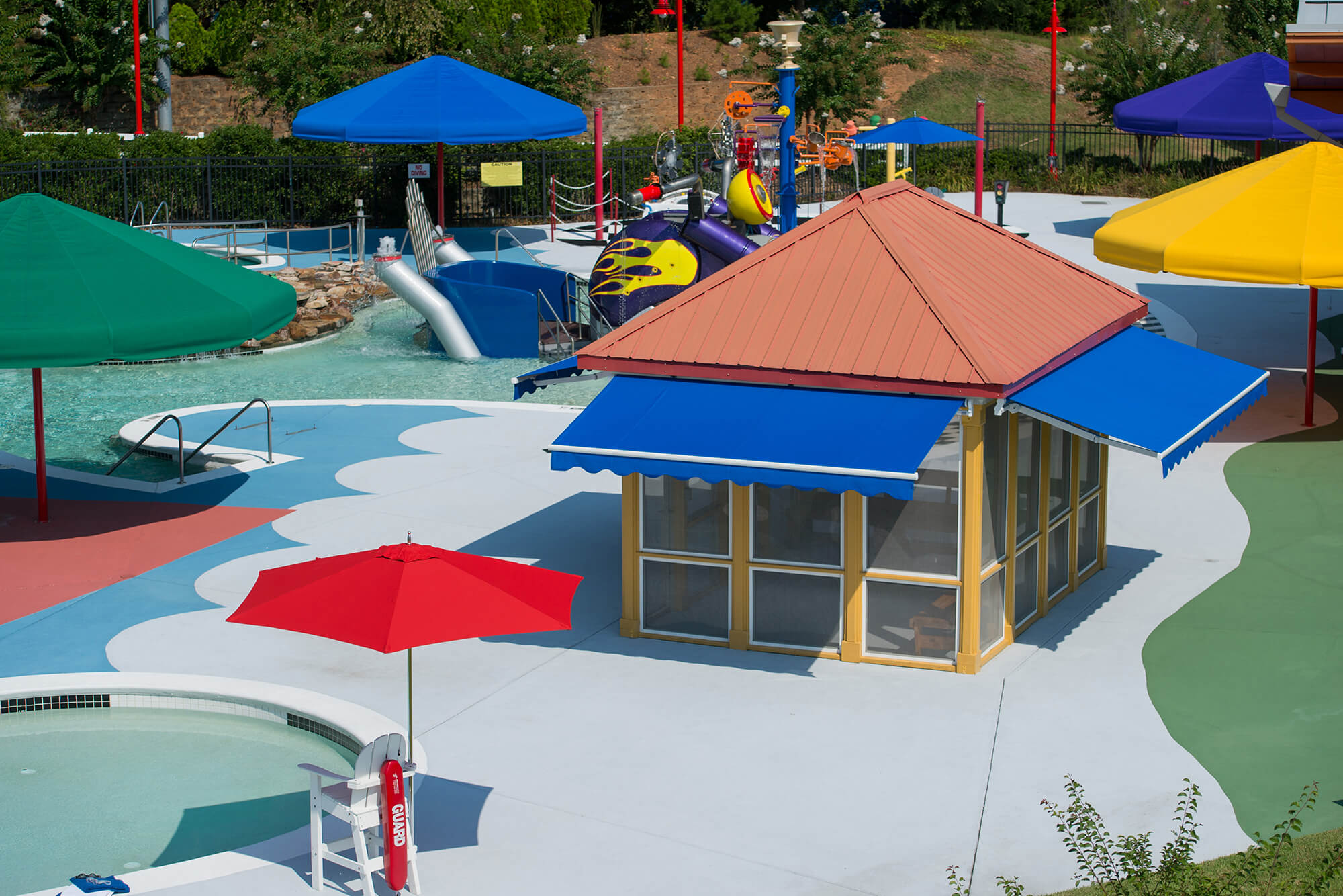 Um parque aquático oferece a sombra de guarda-sóis radiantemente coloridos e chamativos toldos azuis retráteis