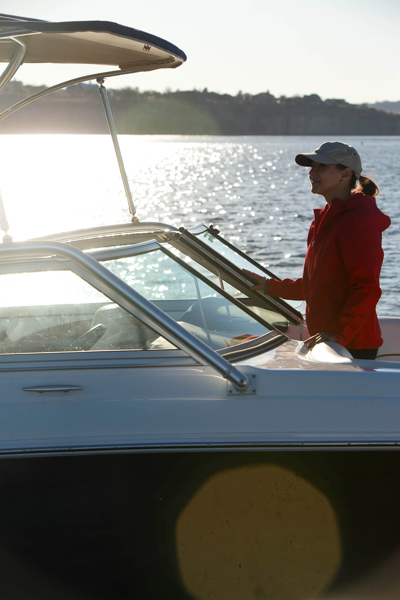 女性が船首に立つ、ネイビーのSunbrella Supremeファブリックを使ったビミニのある電動ボートを前から見たところ