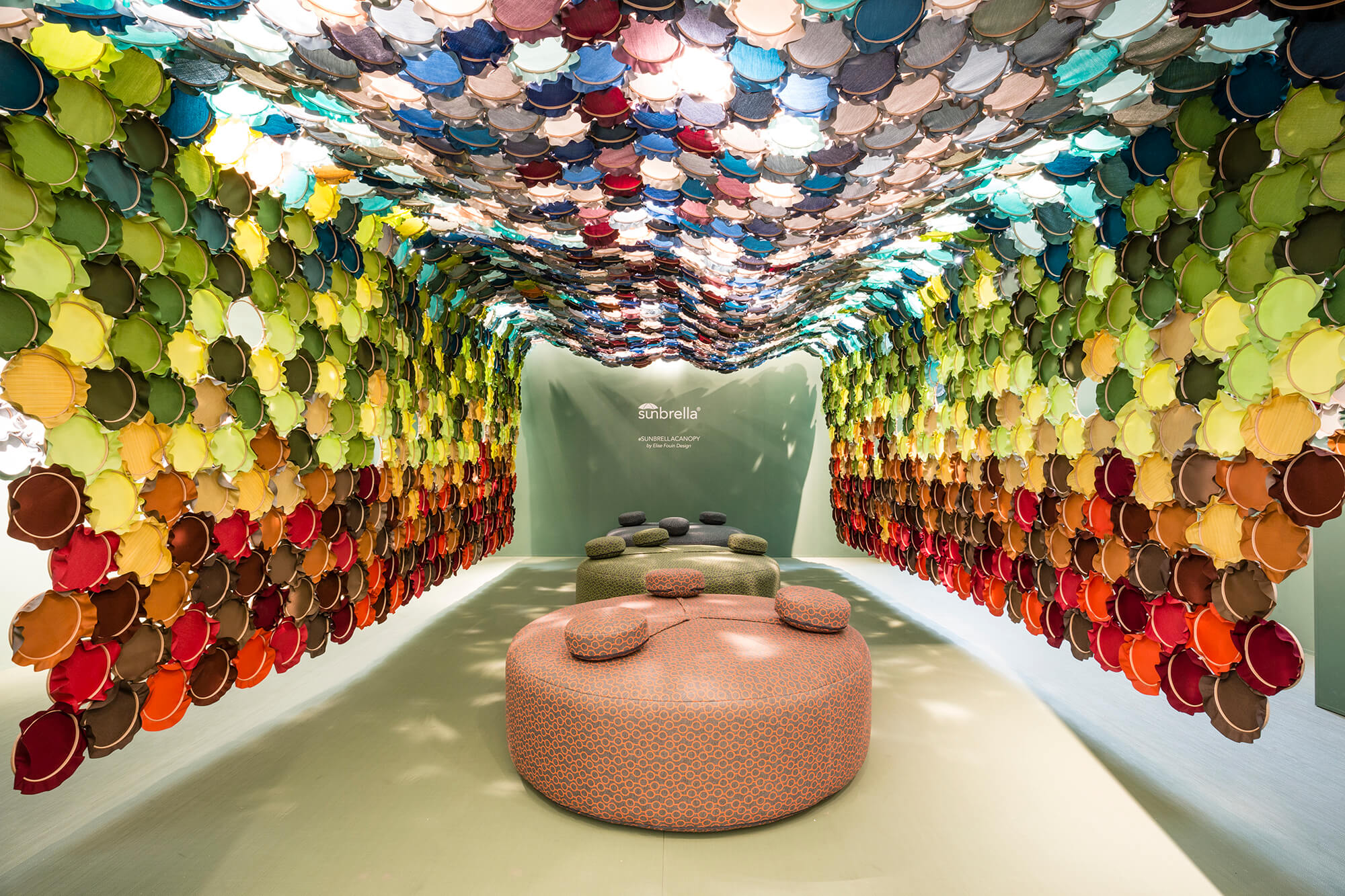 Instalação de arte mostrando radiantes cores de tecidos Sunbrella em aros bordados interligados.