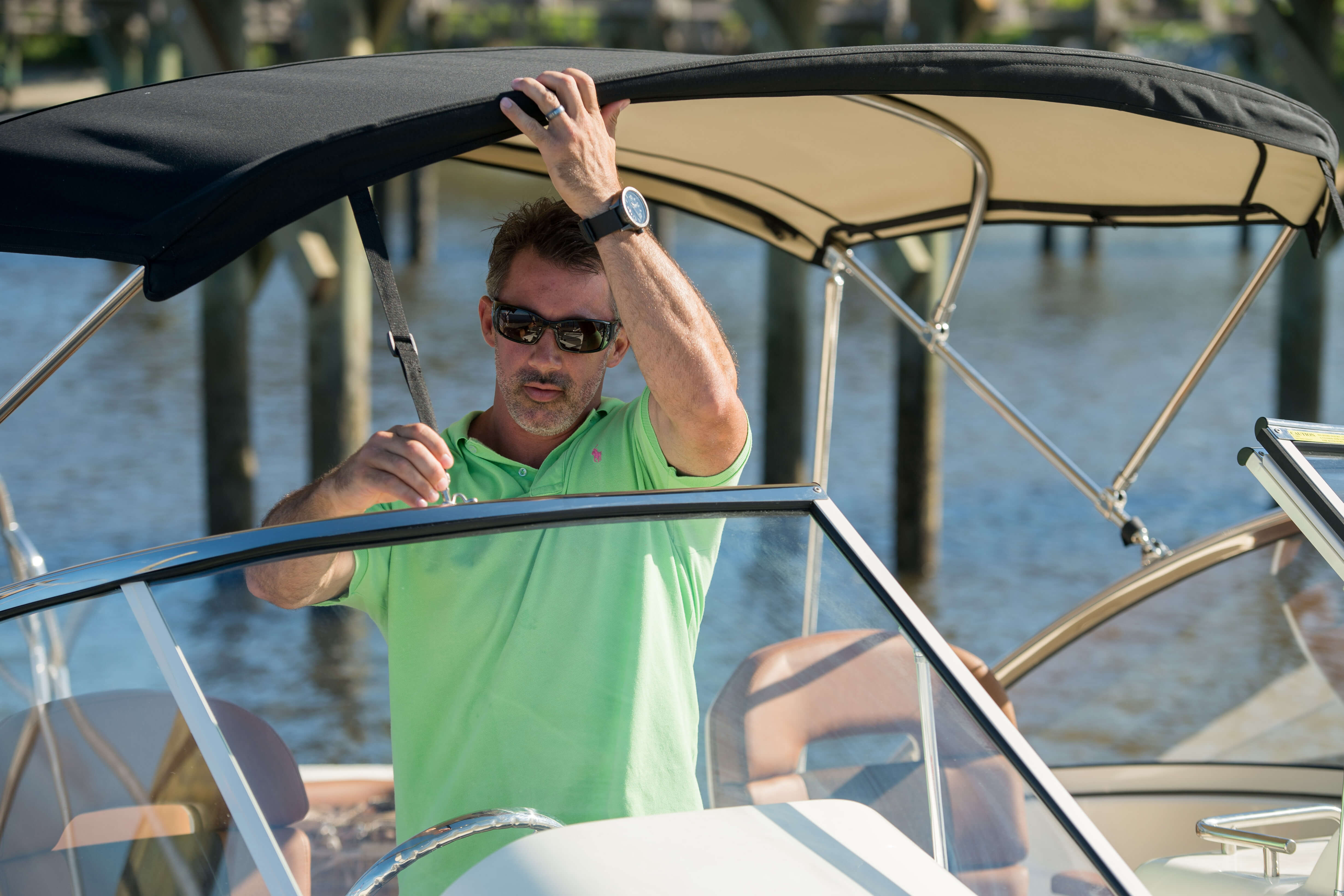 Man installeert een zwarte bimini met Sunbrella Supreme-stof