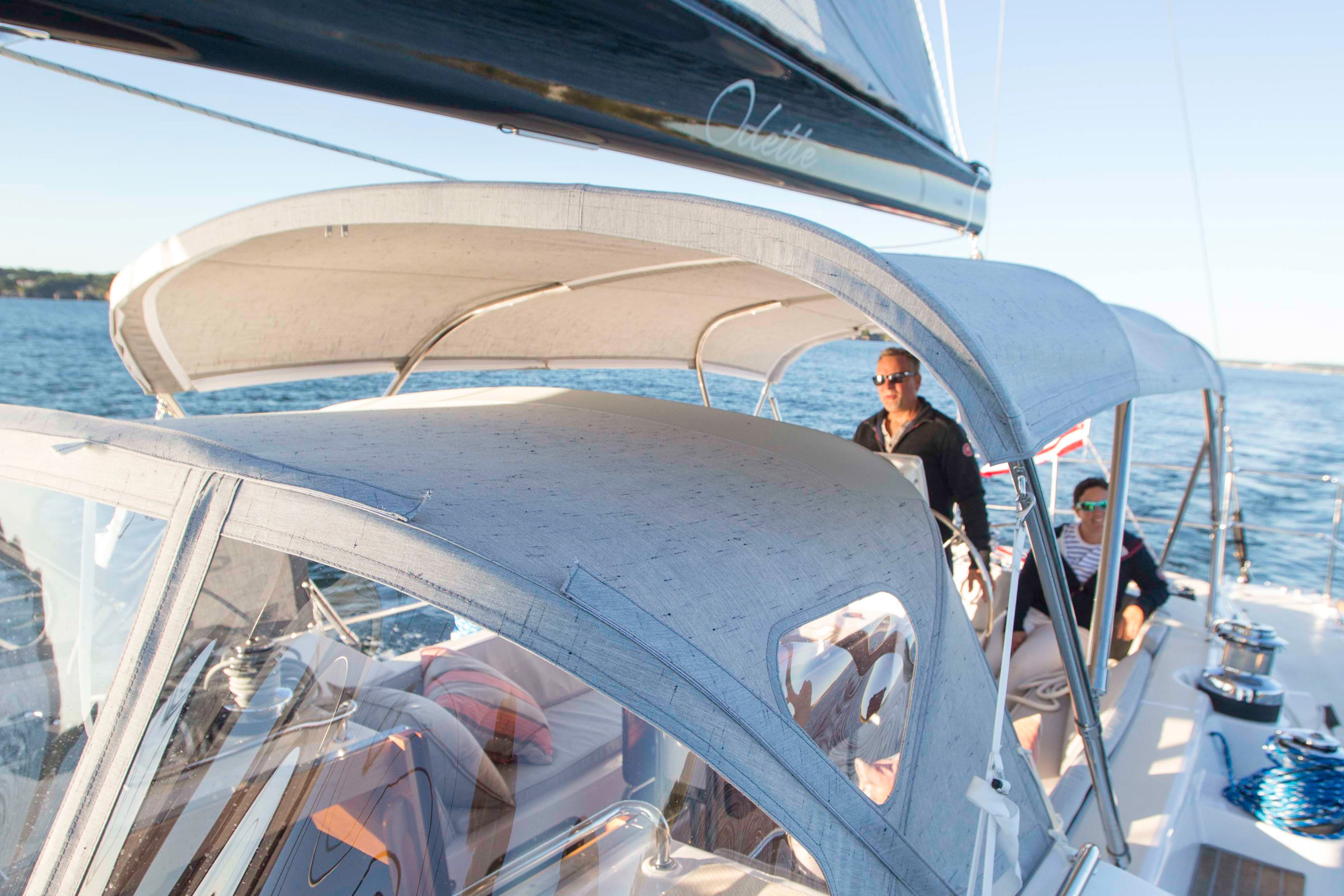 Pärchen auf einem Segelboot mit grauem Bimini und Sprayhood aus Sunbrella-Stoff
