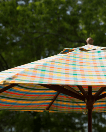 Un ombrellone esterno con un tessuto luminoso a quadri della collezione Sunbrella Shift