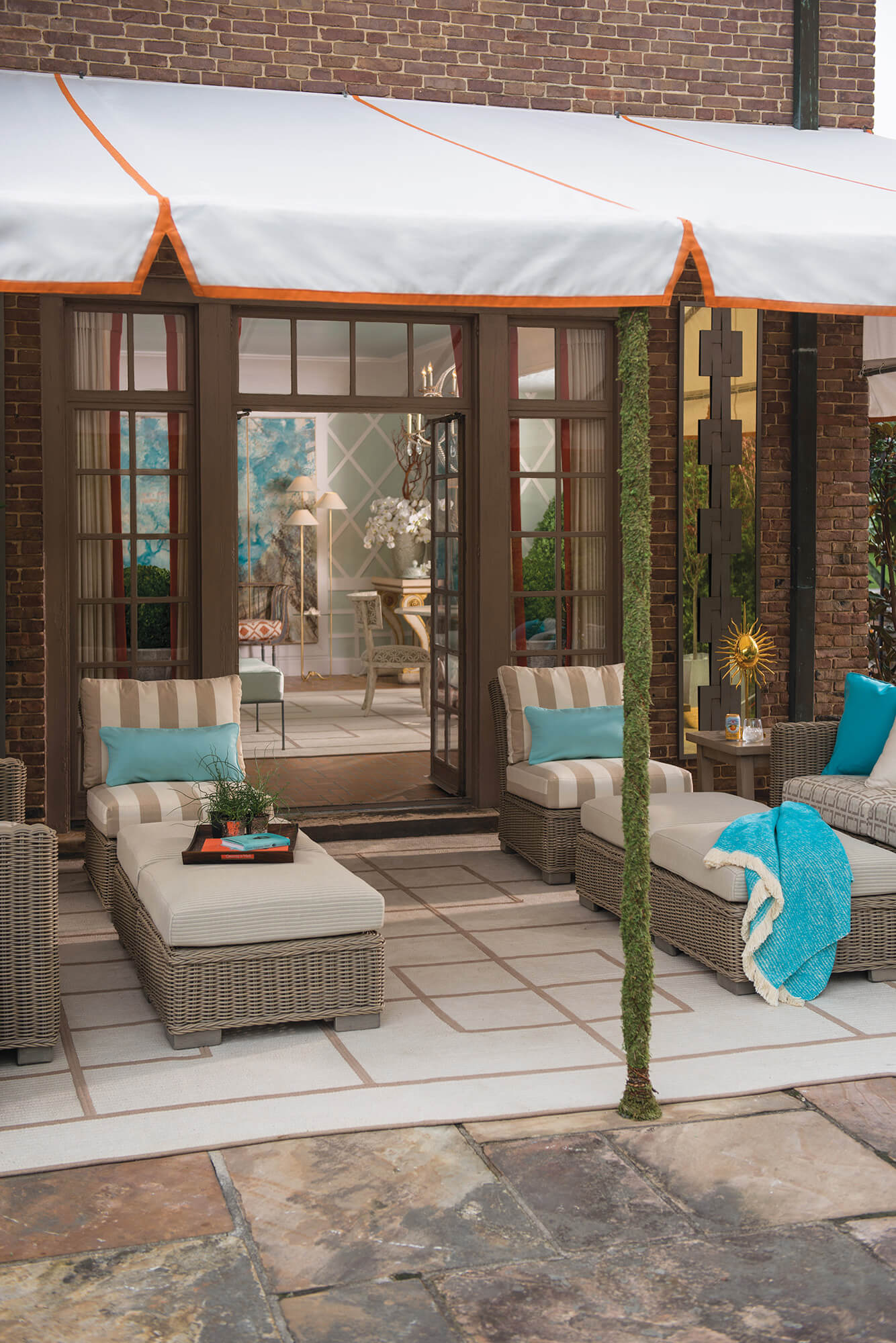 Un toldo blanco de marco fijo con borde naranja da sombra al área para sentarse de un patio en el exterior