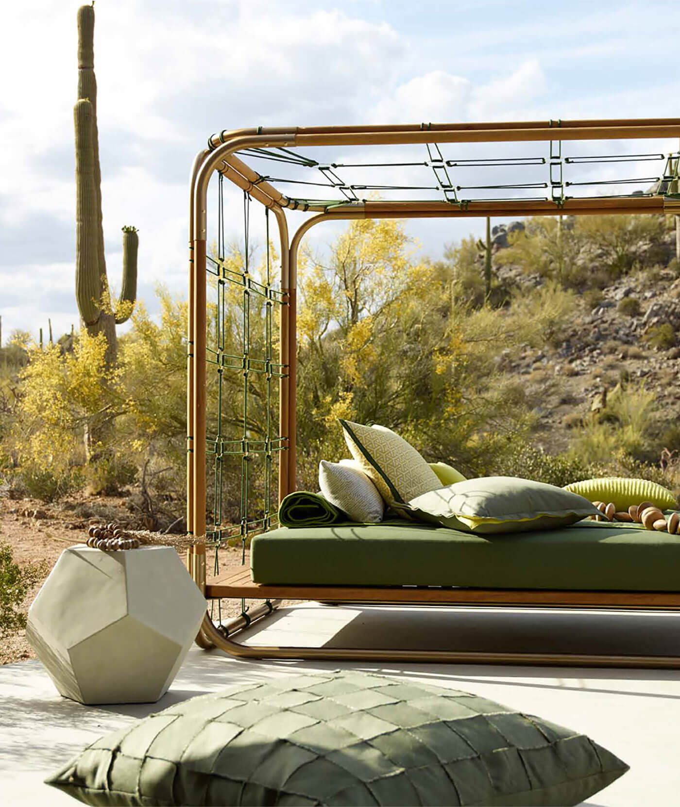 Sofá-cama estofado com tecidos verdes no terraço e diversas almofadas decorativas